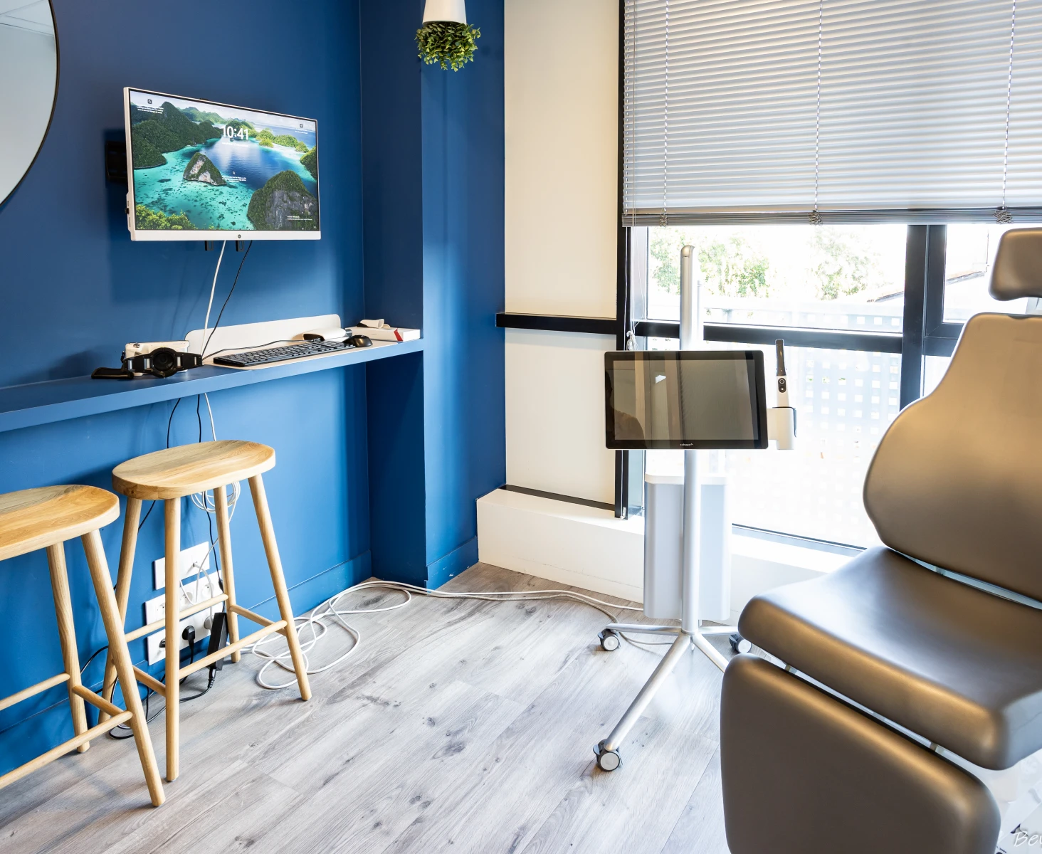 Espace de soins avec tabourets en bois, écran mural et fauteuil de consultation